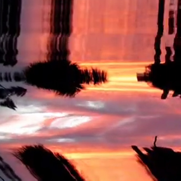 An inverted, distorted image showing the reds, deep blues, and dark shadows of a sunset. These colors don't form a traditional picture, but a more warped abstract one.